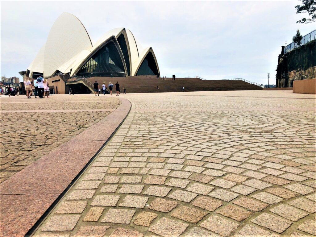 Image of Sydney Opera House forecourt, showing Opera House in background and details of tiles flooring surface in foreground.