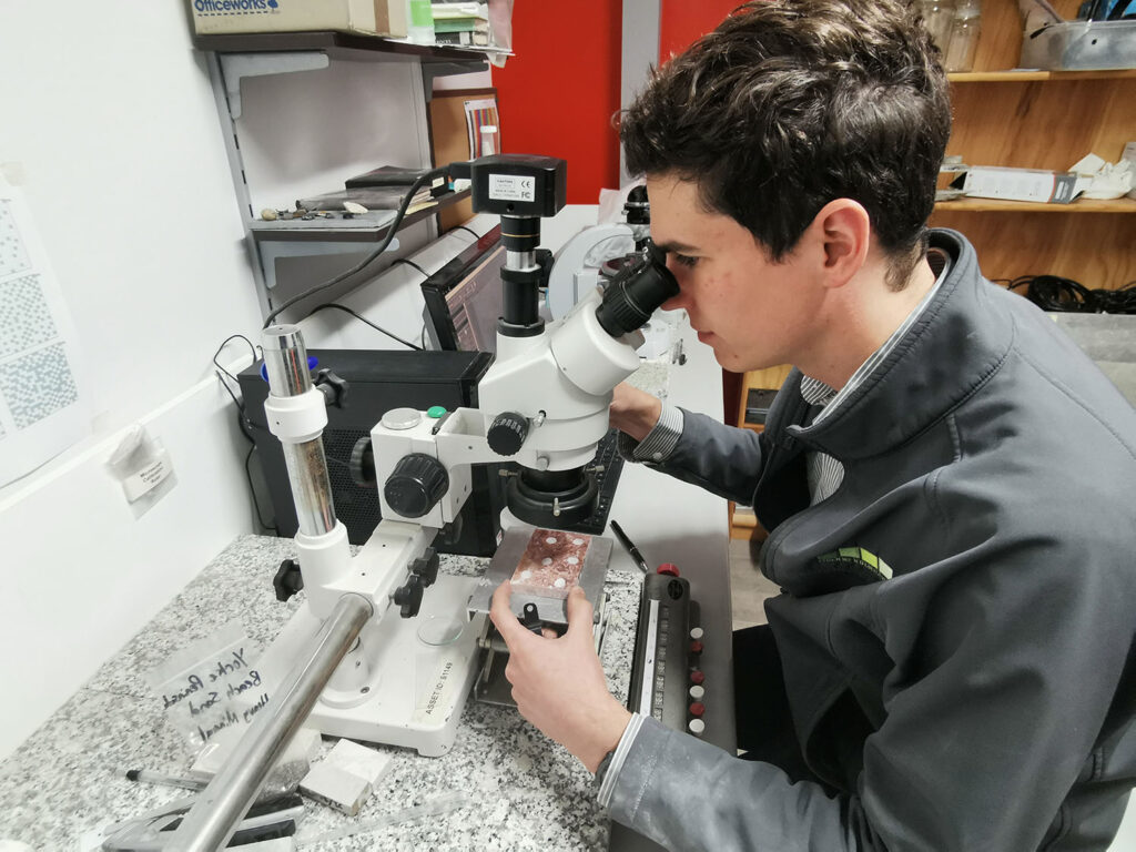 Specialist technician looking through microscope for petrographic analysis