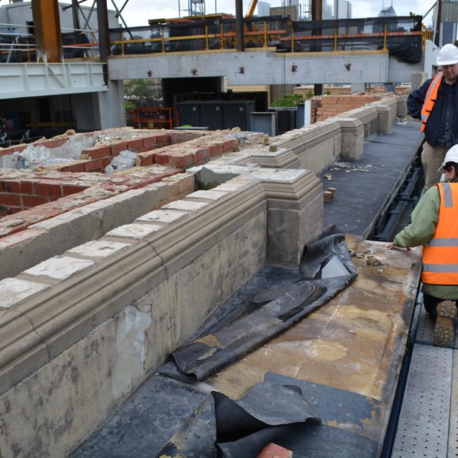 Image of technicians in high-vis vests inspecting heritage wall.