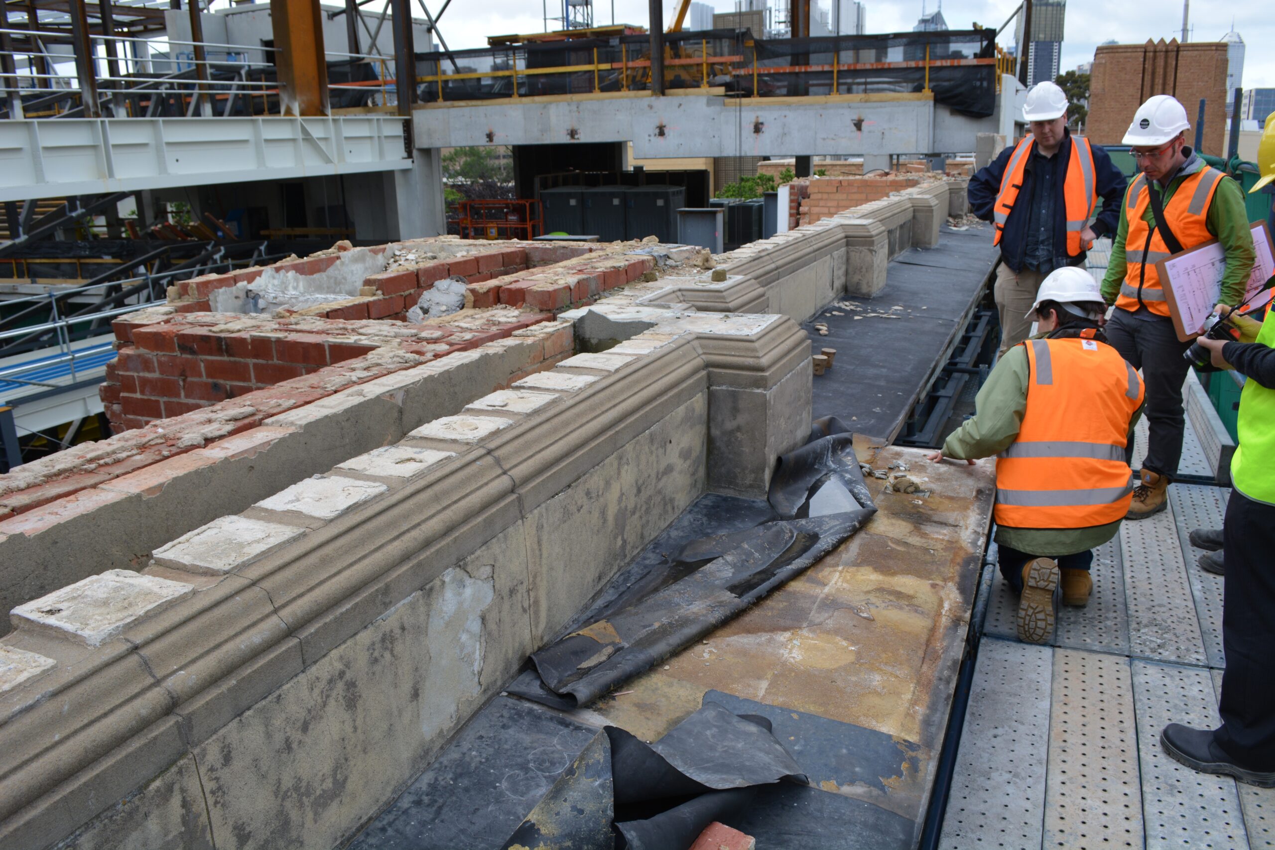 Image of technicians in high-vis vests inspecting heritage wall.